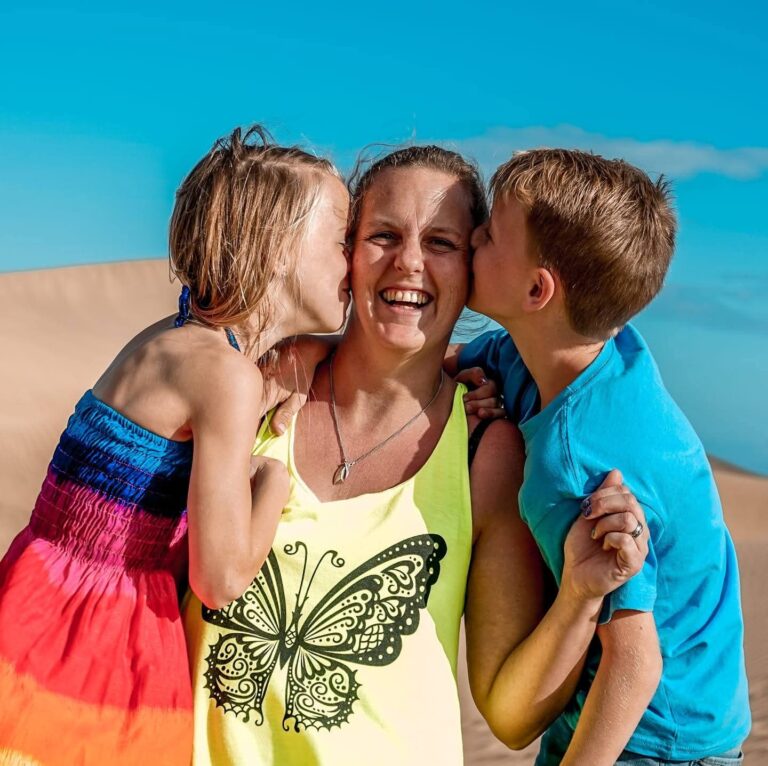 Gastouder Suzanne krijgt van twee kinderen een kus op het strand