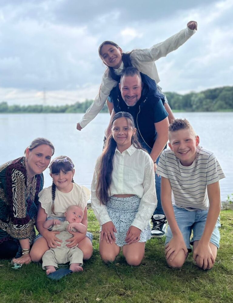 Groepsfoto van gastouder Mikatrien met vijf kinderen aan het water